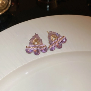 Macro view of purple zircon heart floral earrings on a white ceramic tray detail