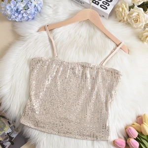 Detail of champagne sequin camisole with thin straps on elegant floral background