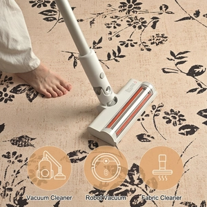 Round cream vacuum cleaner brush head with orange spiral roller on floral carpet