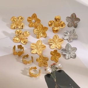 Detailed close-up of gold and silver floral rings with brushed metal texture and pearl accents