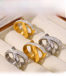 Detailed view of criss-cross X rings in gold and silver finish with sparkling gemstones
