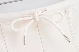 Detail of cream knit shorts featuring braided drawstring with silver metal tips