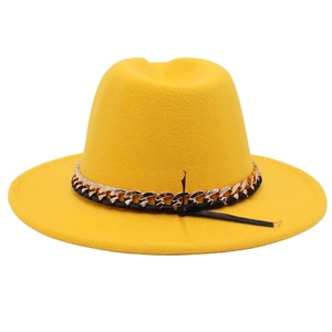 Detail of yellow wool fedora with gold chain trim and black ribbon on white background