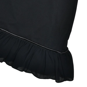 Détail de l'ourlet de la robe noire avec des volants en mousseline et une bordure brillante