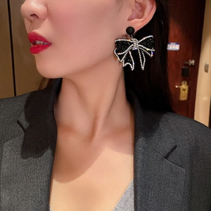 Detailed view of elegant black bow earrings with sparkling silver rhinestones on a model