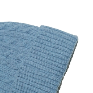 Close-up of light blue cable knit winter hat showing soft yarn texture and ribbed edge