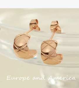 Macro shot of rose gold C-shaped hoop earrings featuring a stylish quilted stripe pattern