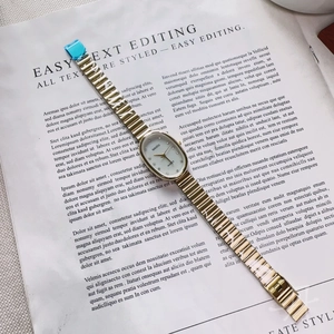 Detail of elegant gold-tone oval watch with a shell dial on a fashion magazine background