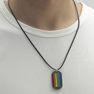 Pendentif plaque arc-en-ciel en acier inoxydable avec cordon noir sur un t-shirt blanc