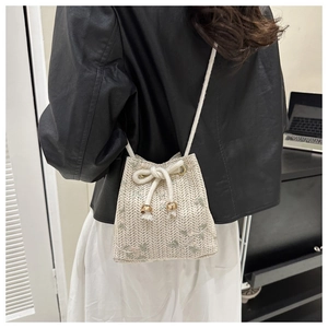 Detail of beige straw bucket bag with floral embroidery and rope drawstring closure