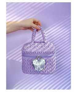 Detail of purple quilted handbag with heart charm featuring silver bow and logo