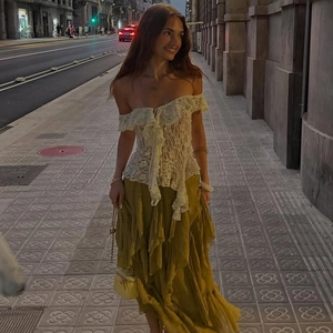 Close-up of white lace off-shoulder top with ruffles and yellow pleated skirt detail