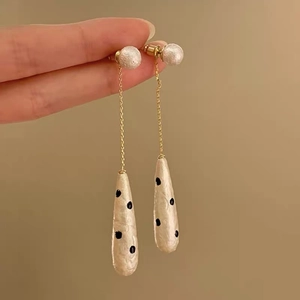 Detail of drop tassel earring with white pearl stud and black polka dot pendant