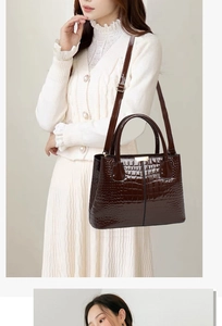 Detail shot of the dark brown crocodile pattern handbag with gold hardware and shoulder strap