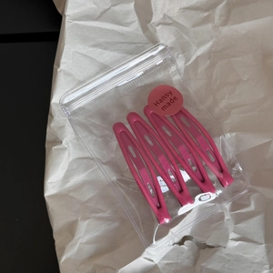 Detailed view of four pink snap hair clips packaged in a branded Hansy made transparent bag