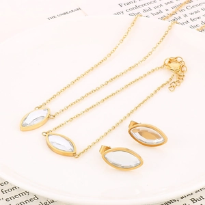 Détail d'un ensemble collier et boucles d'oreilles dorés avec zircon sur assiette blanche