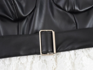 Détail d'une robe en cuir PU avec ceinture à boucle dorée et bordure en dentelle blanche