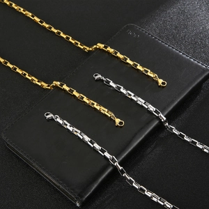 Detail of gold and silver box chains with clasps on a black leather background