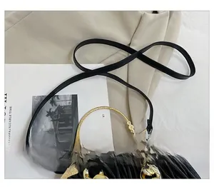 Detail shot of black pleated shell bag with gold round handle and chunky chain strap