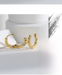 Detailed view of gold plated brass earrings featuring a textured hammered surface finish