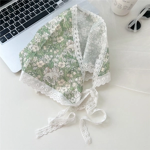Detail of green floral cotton headscarf with delicate white lace edges and ties