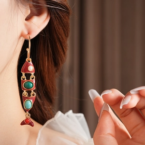 Détail d'une boucle d'oreille poisson vintage en émail rouge avec pierres colorées