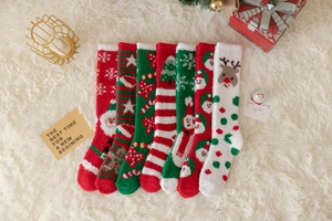 Flachbild von bunten Weihnachts-Korallenfleece-Socken mit festlichen Motiven auf weißem Teppich