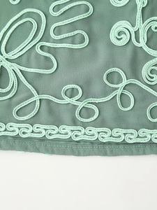 Vue macro du tissu vert de l'ensemble de vacances avec broderie et motifs délicats