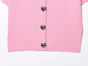 Detail of pink knitted top featuring silver heart-shaped buttons with rope texture