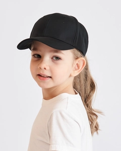 Close-up of a child wearing a classic black ponytail baseball cap on a white background