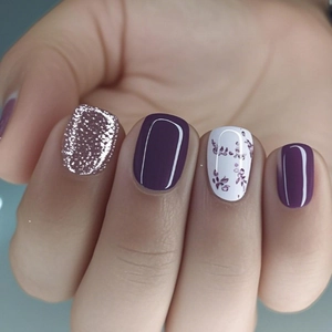 Short round press-on nails with purple floral art, glitter accents and glossy finish
