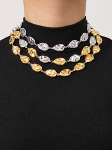 Detail of layered mixed-tone necklaces featuring irregular circular gold and silver disks