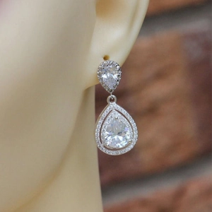 Elegante zilveren druppeloorbellen met kristallen gedragen door een model in close-up