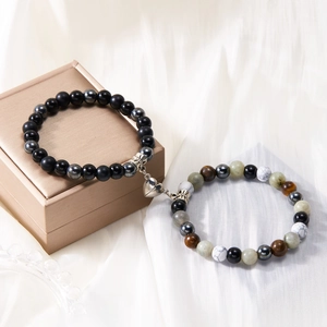 Close-up of natural stone couples bracelets with magnetic heart charm on silk