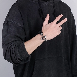 Détail d'un bracelet en cuir nautique avec ancres et gouvernail en argent sur le poignet