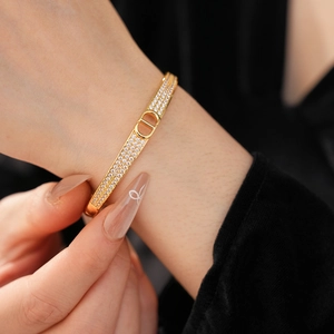 Macro shot of gold-plated fan-shaped bangle with inlaid zircons and CD letter clasp