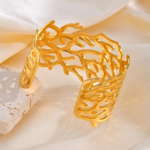 Detailed close-up of a wide gold open cuff bracelet with an organic coral-like texture