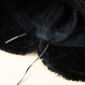 Gros plan d'un bonnet d'hiver en peluche noire avec doublure et cordons de serrage réglables