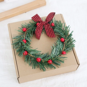 Close-up of Christmas wreath with red berries and plaid bow on craft gift box