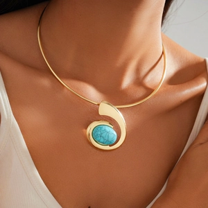 Detail of a gold rigid collar necklace featuring a spiral turquoise stone pendant