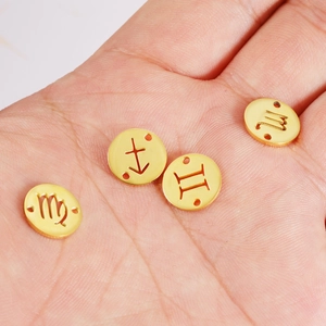 Detailed view of four golden circular zodiac pendants featuring diverse etched horoscopic symbols