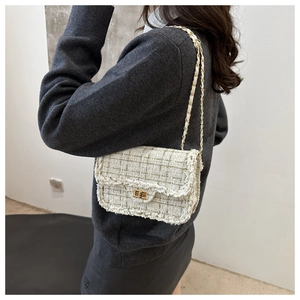 Detail of a beige tweed crossbody bag featuring metallic threads and a gold turn-lock