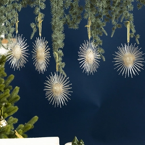 Champagne gold glitter starburst pendant hanging on green Christmas tree branch