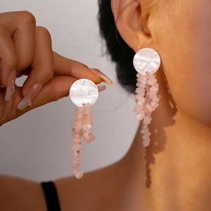 Detail view of long tassel earrings with pink crushed stone beads and white shell-textured studs