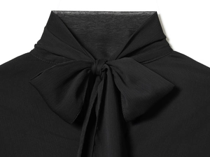 Detalle de blusa de gasa negra con cuello de lazo y textura de tejido de alta calidad