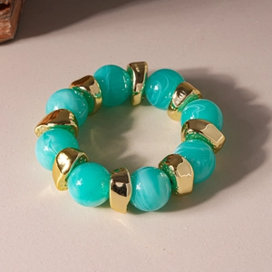 Detailed shot of green resin beads and gold geometric metal spacers on a beaded bracelet