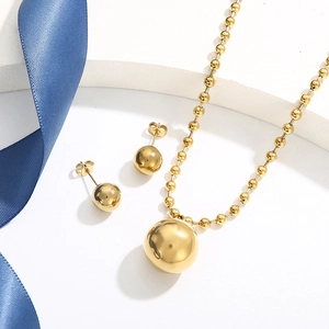 Flat lay of gold beaded jewelry set with round pendant necklace and matching stud earrings