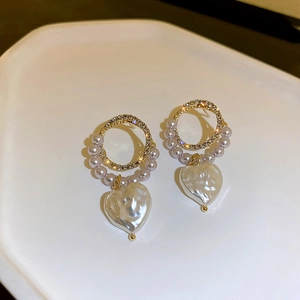 Detail of gold hoop earrings with sparkling rhinestones and heart-shaped baroque pearls