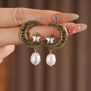Detail of vintage moon and star earrings featuring rhinestones and a white pearl drop