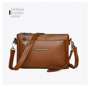 Detail view of yellow brown leather shoulder bag with multi-layer zippers and metal pendant